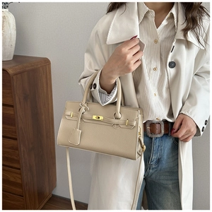 Detail of beige litchi grain leather handbag with gold hardware and shoulder strap