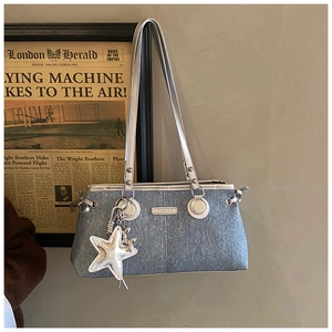 Detail of denim shoulder bag featuring silver 'FASHION' plate and star pendant charm