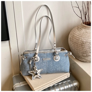 Detail view of denim handbag with silver star charm and fashion metallic logo plaque