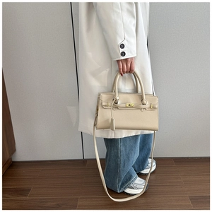 Detail of lychee pattern leather handbag in beige with metallic clasp and long strap