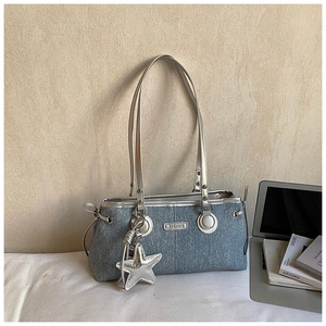 Detail of blue denim shoulder bag with silver star charm and metallic FASHION nameplate