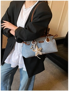 Detail of blue denim tote bag with brown leather trim and silver star charm