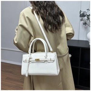 Detail of white lychee pattern leather handbag with gold hardware and top handle