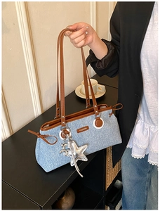 Detail view of denim tote bag with leather handles and a silver star charm