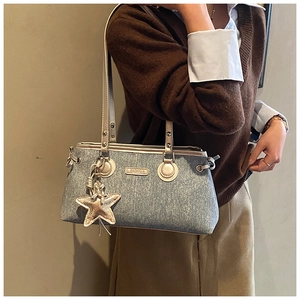 Detail of denim crossbody bag with metallic logo and gold star charm on model