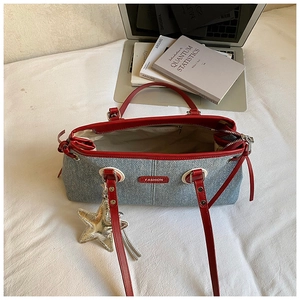 Detail of grey denim tote bag with red leather trim and a gold star charm pendant