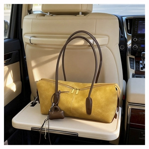 Detail of ginger suede tote bag with brown straps placed on a luxury car tray table
