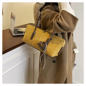 Detail of yellow suede hobo bag with brown leather strap and stylish tassel accent