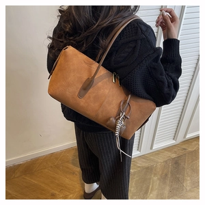 Brown suede underarm bag with zebra print charm shown in a realistic lifestyle setting