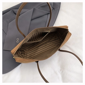 Detailed interior of brown tote bag with striped lining and zipper pocket
