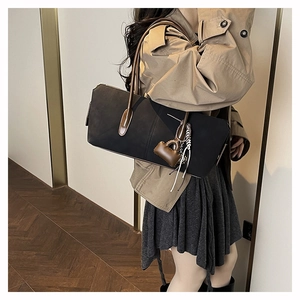 Minimalist black tote bag with brown leather straps shown on model in a modern interior