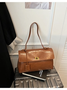 Detail of caramel oil wax leather shoulder bag with gold turn-lock and side charm