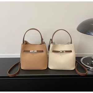 Détail de sacs seaux en cuir grainé avec fermoir métallique et fermeture à lanière