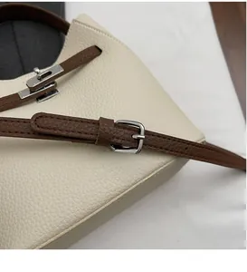Détail du sac en cuir grainé blanc cassé avec bandoulière marron et boucle argentée