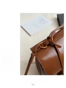 Detailed macro view of golden metal buckle and stitching on brown vintage shoulder bag