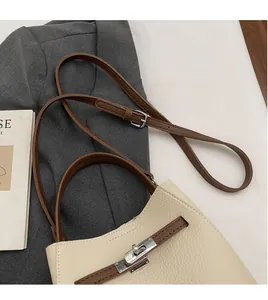 Gros plan d'un sac à main en cuir grainé avec une bandoulière réglable lisse de couleur marron