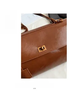 Close-up of vintage bronze buckle on brown lychee texture leather handbag with stitching