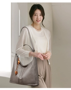 Détail d'un sac cabas en cuir gris foncé avec poches avant et charme en perles de bois