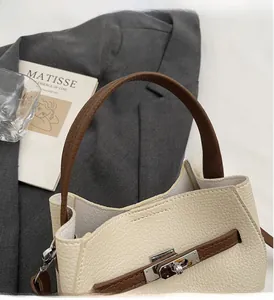 Détail du sac à main en cuir crème avec fermoir argenté sur un blazer gris