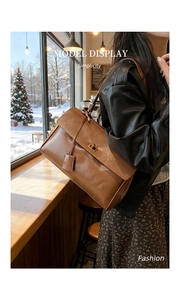 Detail view of a vintage brown leather shoulder bag with a gold twist lock and a flap design