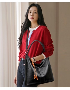 Détail du sac à main en similicuir noir avec pompon orange et bandoulière réglable