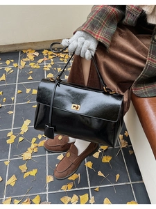 Detail of vintage black patent leather briefcase featuring a gold-tone square twist lock