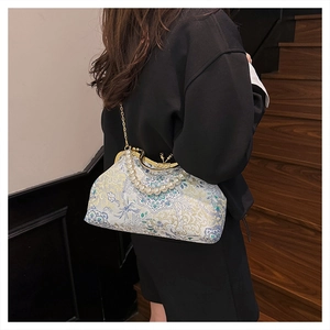Close-up of floral brocade evening bag with pearl handle and metal chain on stairs