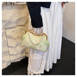 Close-up of floral jacquard evening bag with large pearl handle and gold chain strap
