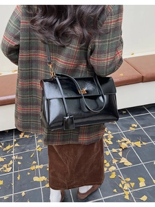 Detailed macro view of black glossy leather bag with golden rotary metal buckle closure
