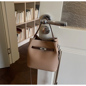 Détail du sac seau avoine avec fermoir argenté et poignée marron sur une porte