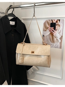 Macro detail of creamy beige faux leather shoulder bag with golden twist lock buckle