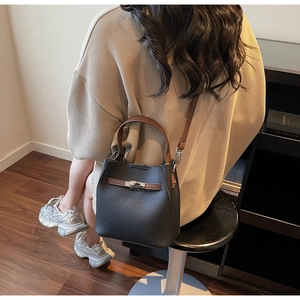 Vue détaillée d'un sac seau en cuir noir avec poignées marron et fermoir argenté poli