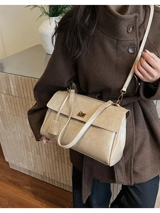 Cream vintage leather bag with gold twist lock shown on model in brown wool coat