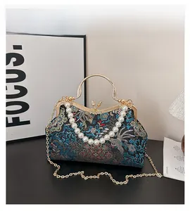 Close-up of floral embroidery detail with pearl handle and golden chain on evening bag