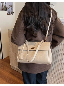Close-up of beige vintage Kelly shoulder bag with golden twist lock and textured leather