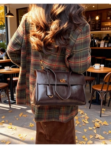 Detail of vintage brown leather handbag with gold twist lock on autumn coat background