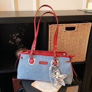 Retro denim shoulder bag with red trim and star pendant in a casual still life setting