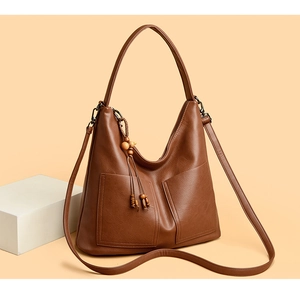 Gros plan du sac en cuir marron vintage avec pompon en bois et poches frontales
