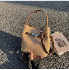 Détail du sac seau en cuir beige avec boucle métallique et bandoulière contrastée
