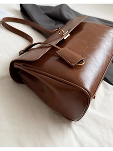 Close-up of vintage brown faux leather shoulder bag with bronze hardware and matte finish