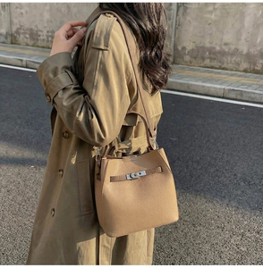 Détail du sac seau kaki avec cuir grainé et fermoir en métal argenté porté par un mannequin