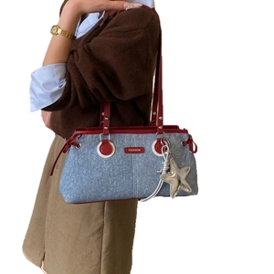 Denim shoulder bag with red contrast trim and star charm shown on model in studio
