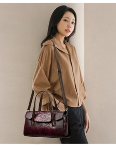 Dettaglio del motivo floreale a rose su borsa in pelle bordeaux con manici