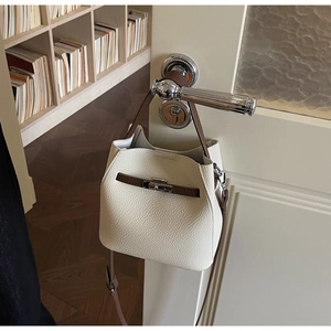 Détail du sac seau blanc crème avec poignées en cuir marron et fermoir rotatif argenté