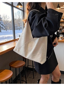 Close-up of the embossed texture and triangular design of the white leather tote bag
