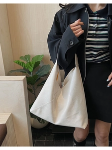 Detail of soft cream leather tote with V-cross design and textured lychee pattern finish