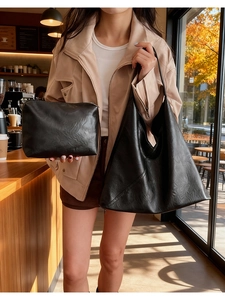 Detail view of black pleated texture tote bag and matching pouch in an outdoor cafe setting