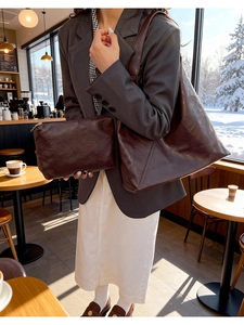 Detail of dark brown vintage leather tote bag and inner pouch in a cafe setting