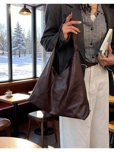 Deep brown large capacity leather hobo bag styled in a cozy winter cafe setting