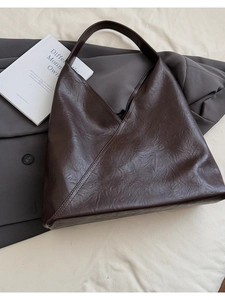 Close-up of vintage brown leather tote bag with unique V-shaped stitched pleats